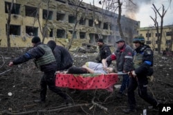 Az egyik mariupoli szülészetet érő orosz támadás után viszik ki az egyik sérült, várandós nőt a mentősök március 9-én. Később az ukrán hatóságok közölték, a baba halva született, és fél órával később az anya is meghalt