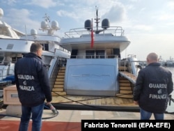Procurorii financiari italieni contemplând un iaht rusesc confiscat la Sanremo la câteva zile după invazia rusă pe scară largă din Ucraina.