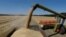 A combine harvester loads a truck with barley in a field near the village of Zhovtneve, Ukraine.