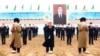 Oficiali turkmeni pe fundalul unei imagini a președintelui Serdar Berdîmuhamedov, care a preluat funcția de la tatăl său, în martie 2022. 