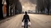 A man walks holding shopping bags near a burning warehouse hit by a Russian shell in the suburbs of the Ukrainian capital, Kyiv.&nbsp;