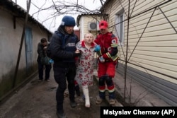 Фотограф Євген Малолєтка і парамедик допомагають пораненій жінці у Маріуполі, 2 березня 2022 року.