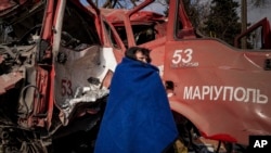 Женщина укрывается одеялом возле поврежденной пожарной машины после обстрела в Мариуполе, Украина, 10 марта 2022 года. Иллюстративное фото.