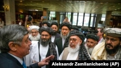 Trimisul președintelui Rusiei în Afganistan Zamir Kabulov, stânga, morbește cu mulahul Abdul Ghani Baradar, lider al grupării talibanilor