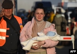 O refugiată din Ucraina traversând granița pe la Isaccea, România, alături de copilul ei, 24 martie 2022.