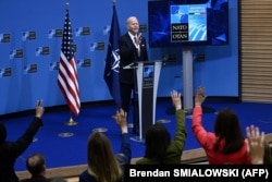 JAV prezidentas Joe Bidenas rodo gestus, žiniasklaidos atstovams pakeldamas rankas, kad jį paklaustų per spaudos konferenciją NATO būstinėje Briuselyje kovo 24 d.