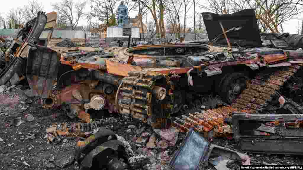 Уничтоженный российский танк Т-72 возле поврежденного мемориала погибшим воинам во Второй мировой войне в селе Лукьяновка Киевской области.
