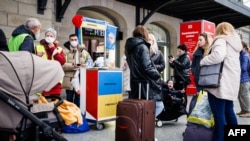 Украинские беженцы стоят у информационного стенда на главном железнодорожном вокзале (Hauptbahnhof) в Дрездене, Германия, 22 марта 2022 года