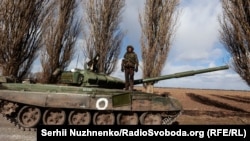 Український військовослужбовець стоїть на захопленому в бою російському танку Т-72 у селі Лук'янівка, що на Київщині, 27 березня 2022 року