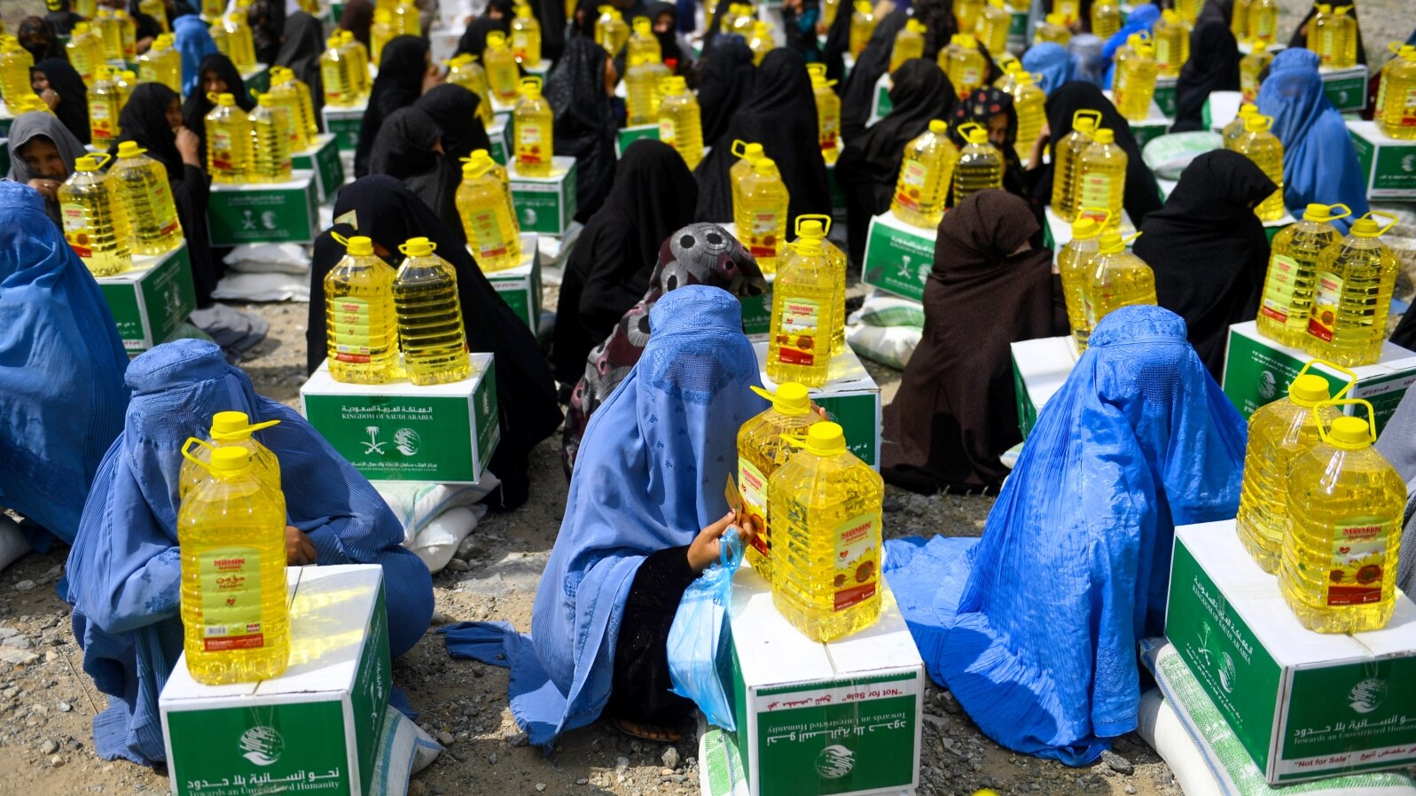 FILE: Afghan women receive food aid in the western province of Herat in May.