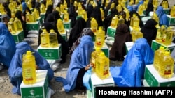 FILE: Afghan women receive food aid in the western province of Herat in May.