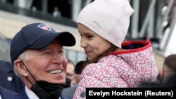 Președintele Statelor Unite Joe Biden ține în brațe o fetiță în timpul vizitei la stadionul PGE National, unde sunt adăpostiți refugiați ucraineni, Varșovia, 26 martie 2022