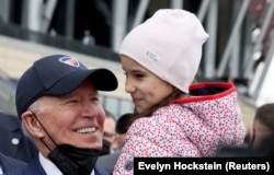 Президент США Джо Байден держит на руках девочку, которая была вынуждена спасаться от войны в Украине, Варшава, Польша, 26 марта 2022 года