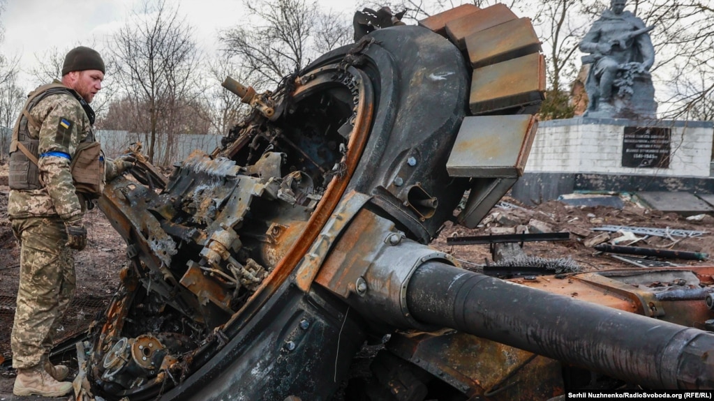 Një ushtar ukrainas inspekton mbetjet e një tanku të shkatërruar rus në fshatin Lukianivka të çliruar së fundmi në rajonin e Kievit, më 27 mars.