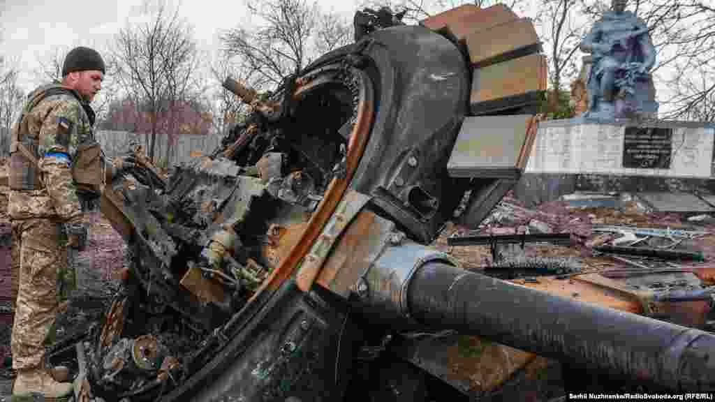 Украинский военный осматривает остатки уничтоженного российского танка в недавно освободившемся селе Лукьяновка Киевской области, Украина, 27 марта 2022 года.
