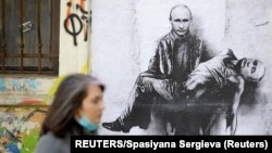 O femeie trece pe lângă o pictură care îl înfățișează pe președintele rus Vladimir Putin ținându-și propriul corp, în timp ce invazia Rusiei în Ucraina continuă. Sofia, Bulgaria, 28 martie 2022.