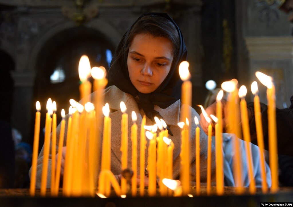 Një e re ndez qirinj gjatë meshë të së dielës në Kishën Katolike të Shën Pjetrit dhe Palit Garrison në qytetin perëndimor të Ukrainës, Lviv.