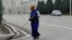 Turkmenistan. Woman with mask cleaning the street of Ashgabat. State white building. Cars. March, 2022 