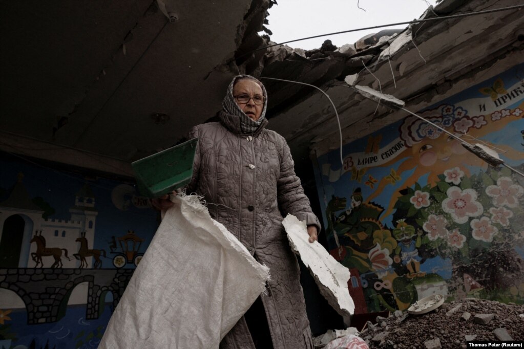 Një grua duke pastruar rrënojat, në një shkollë të dëmtuar nga bombardimet. (Harkiv, 27 mars)