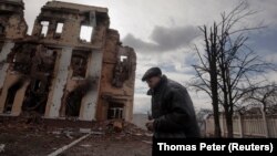 Мужчина проходит мимо школы, которая пострадала в результате боевых действий в Харькове. 27 марта 2022 года. REUTERS/Thomas Peter