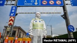 Egy védőfelszerelést viselő hivatalnok 2022. március 28-án Sanghajban a koronavírus elleni intézkedésként lezárt alagút ellőtt. Március 28-án Sanghaj keleti fele zárlat alá került, hogy megfékezzék a járványt.