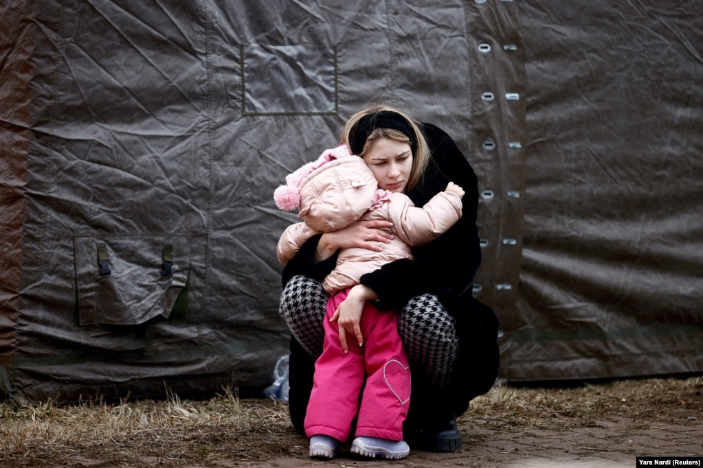 Një grua e ikur nga lufta e nisur nga Rusia në Ukrainë, duke përqafuar një fëmijë, në një kamp të përkohshëm. (Pshemyshël, Poloni, 28 shkurt)