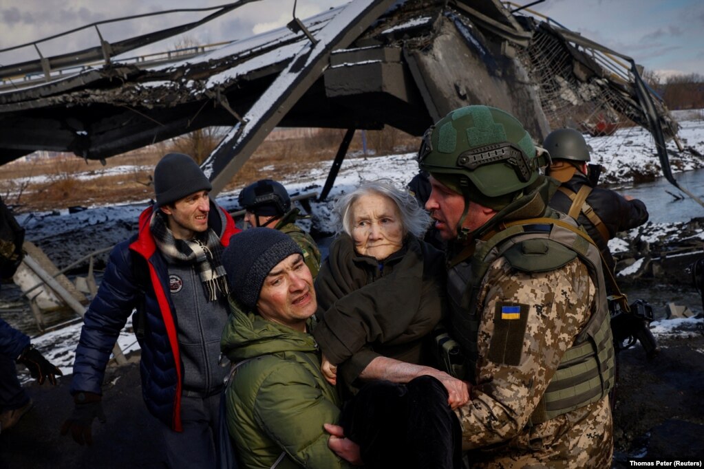Dy burra duke bartur një grua, teksa njerëzit iknin nga trupat ruse. (Irpin, 8 mars)
