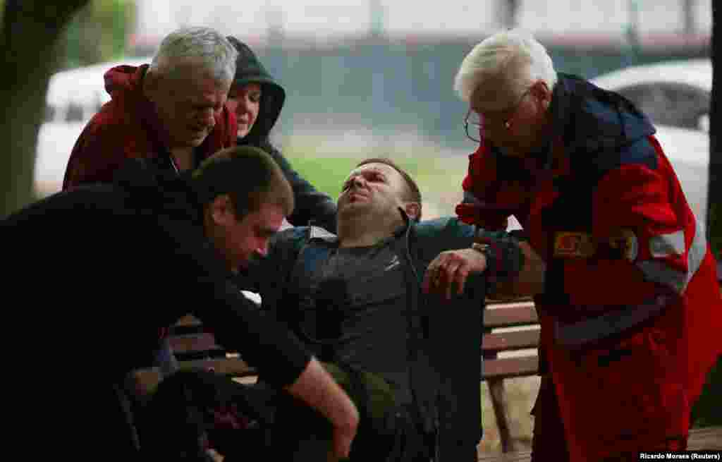 Lucrători medicali îl ajută pe un bărbat care a fost grav rănit în timpul unui bombardament la Harkov pe 27 aprilie.