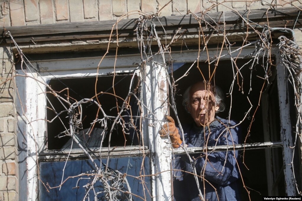 Një burrë duke kontrolluar një dritare të thyer gjatë sulmeve ruse. (Kiev, 26 shkurt)