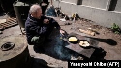 Чоловік готує їжу біля одного з укриттів у Сєвєродонецьку, 27 квітня 2022 року