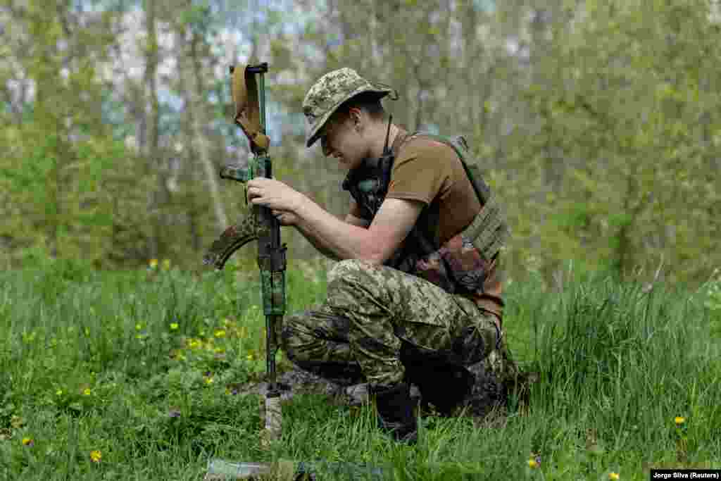 A Ukrainian fighter cleans his rifle while on duty near the front line in Svyatohirsk on April 27.&nbsp;