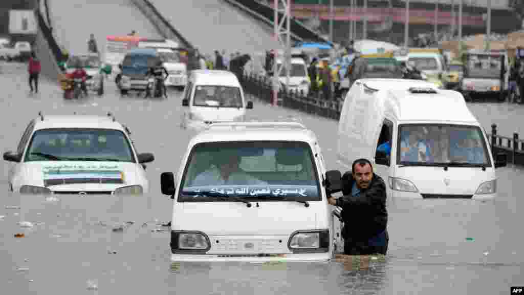 OCTOBER 25, 2012 -- A Syrian man pushes his car after it stopped in a flooded avenue following heavy rain in the northern Syrian city of Aleppo. (AFP/Philippe Desmazes) 