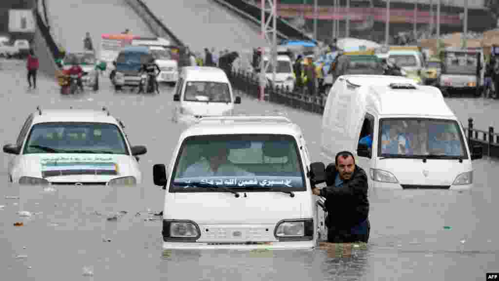 OCTOBER 25, 2012 -- A Syrian man pushes his car after it stopped in a flooded avenue following heavy rain in the northern Syrian city of Aleppo. (AFP/Philippe Desmazes)