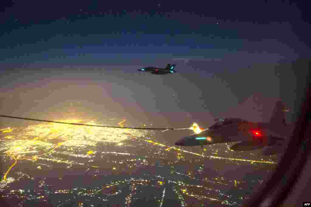 A handout photo shows two Royal Australian Air Force (RAAF) F/A-18F Super Hornet aircraft refueling above a city in Iraq. A Super Hornet fighter jet carried out Australia's first bombing raid in Iraq, targeting what the Defense Ministry described as a "facility" of the Islamist State group. (AFP)