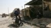 An Iraqi police officer moves debris off the main road following a double explosion in the Sadr City district of Baghdad.