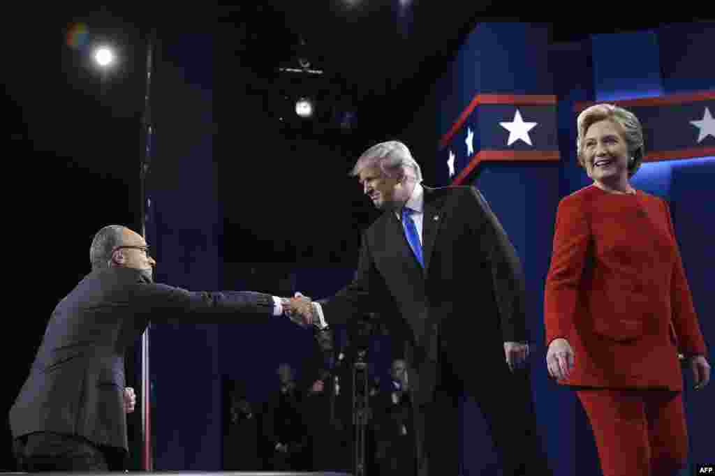 Дональд Трамп, кандидат от Республиканской партии, пожимает руку модератору дискуссии Лестеру Холту. Хиллари Клинтон улыбается зрителям
