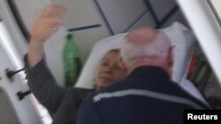 Yulia Tymoshenko waves from a stretcher as she is being transported to an ambulance in Kharkiv on April 22.