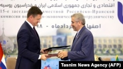 IRAN -- Russian Energy Minister Aleksandr Novak (L) exchanges signed agreements with Iranian Energy Minister Reza Ardakanian during Economic conference in Isfahan, June 18, 2019