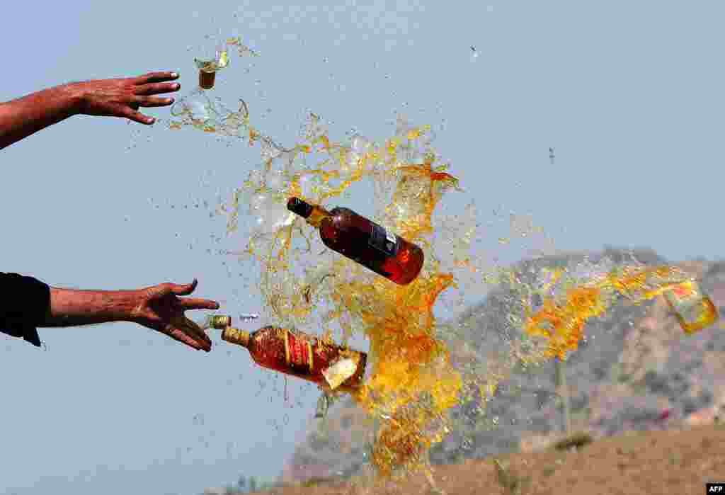 Frontier Corps personnel break liquor bottles in a ceremony in the Shahkas area of the Jamrud Khyber Agency, one of the Federally Administered Tribal Areas of Pakistan. Officials destroyed the contraband as part of International Antidrug Day. (AFP/A Majeed)