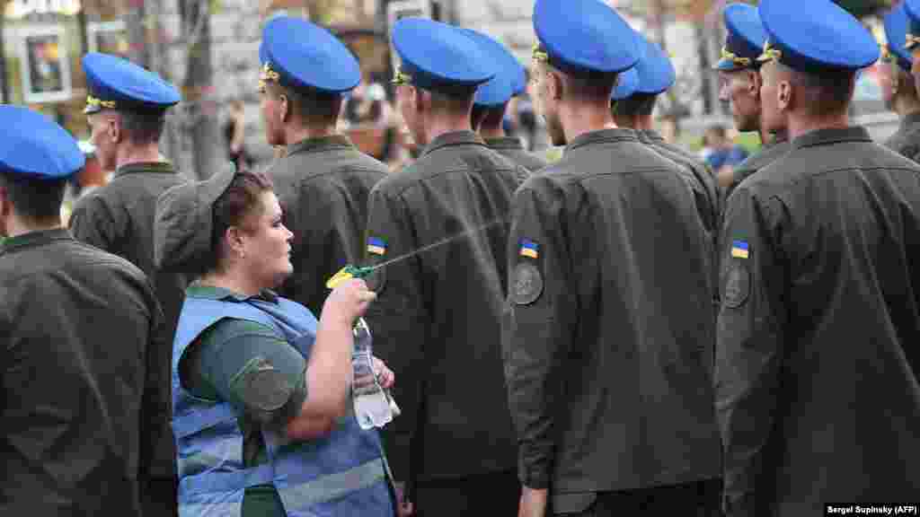 Тәуелсіздік күніне орай өтетін әскери парадқа дайындалып жатқан әскреилерге күн ыстық кезде су шашып, дем беріп тұрған әскери дәрігер.