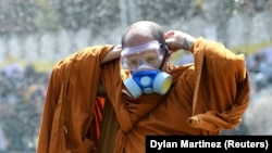 یک راهب بودایی در جمع معترضان ماسک ضدگاز به‌صورت خود می‌زند