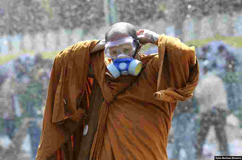 A Buddhist monk puts on a gas mask as riot police use water cannon and tear gas during antigovernment protesters&#39; attempts to remove barricades outside Government House in Bangkok,Thailand. (Reuters/Dylan Martinez)