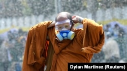 Буддистский монах надевает респиратор во время полицейской газовой атаки