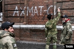 Men from Chechnya's Akhmat Volunteer Battalion paint graffiti reading "Akhmat Is Power" in Mariupol in April.