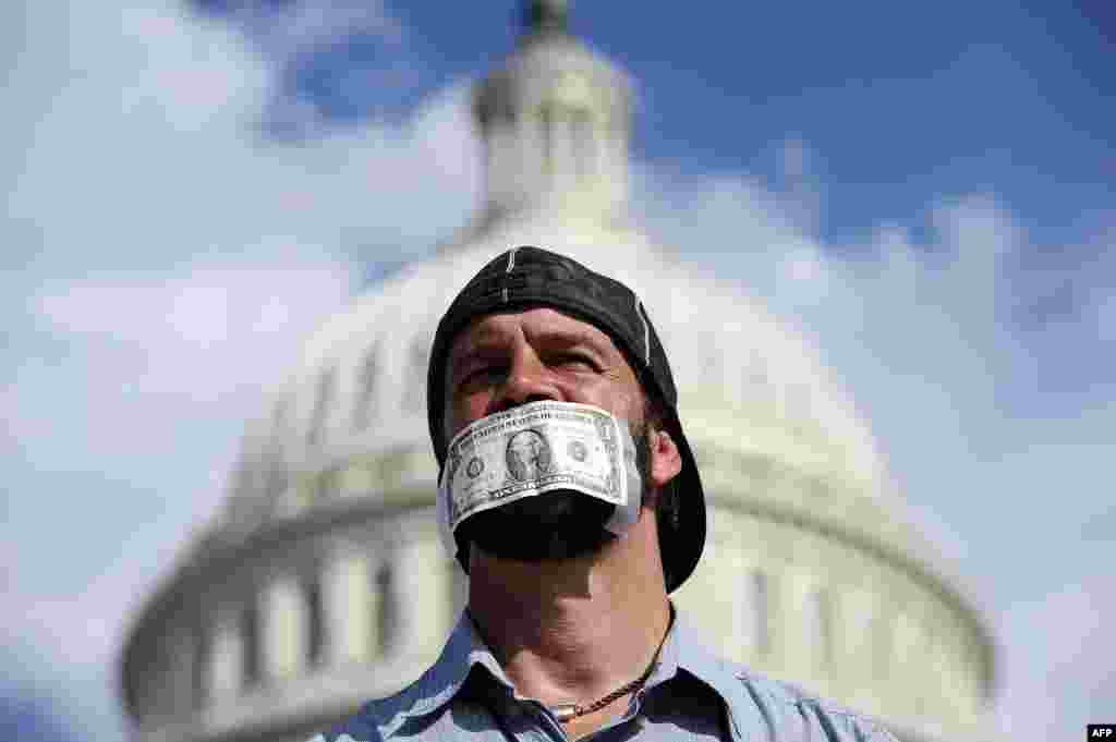 A protester covers his mouth with a dollar bill as he joins others in front of the U.S. Capitol in Washington, D.C., to urge Congress to pass a budget bill to keep the federal government from shutting down. (AFP/Jewel Samad)