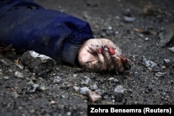 A képen egy nő keze látható, akit a lakosok szerint az orosz hadsereg katonái öltek meg Bucsában