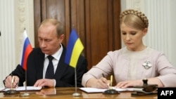 Then-Russian Prime Minister Vladimir Putin (left) signs a gas supply deal with his Ukrainian counterpart, Yulia Tymoshenko, in Yalta in November 2009.