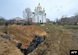 O groapă comună, săpată în apropierea unei biserici din localitatea Bucea, aflată la nord-vest de Kiev, Ucraina. Primarul localități, Anatolie Fedoruk, a transmis reporterilor ca alte 280 de cadavre se află îngropate în gropi comune, săpate pe teritoriul Bucei. Aproximativ 57 au fost găsite doar în cea fotografiată deasupra.