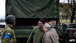 Idős nő ölel át egy ukrán katonát a felszabadult Bucsában, ahol a polgármester szerint 280 embert temettek tömegsírba. A kép 2022. április 2-án készült
