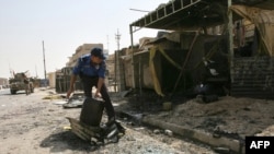An Iraqi police officer moves debris off the main road following a double explosion in the Sadr City district of Baghdad.